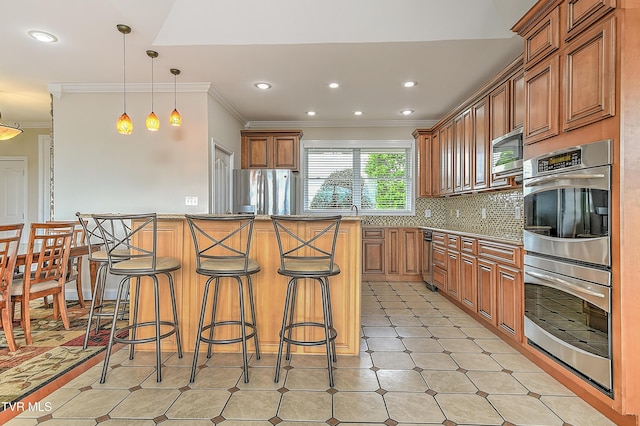 260 Dominique Ln, Greeneville, TN 37743 - kitchen with crown molding, brown cabinets, appliances with stainless steel finishes, a breakfast bar, and decorative backsplash
