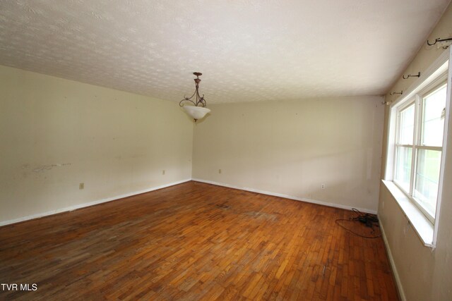 empty room with baseboards, wood-type flooring, and a textured ceiling