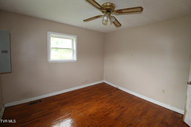 spare room with ceiling fan, hardwood / wood-style floors, baseboards, visible vents, and electric panel