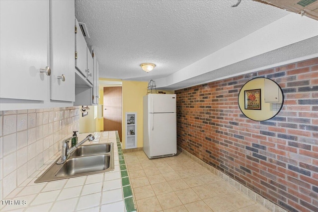 196 Furches Dr, Gray, TN 37615 - kitchen with freestanding refrigerator, tile countertops, a sink, brick wall, and a textured ceiling