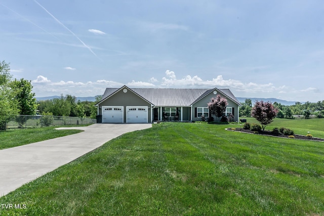 single story home with a garage, fence, metal roof, a front lawn, and concrete driveway