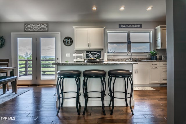 kitchen featuring a sink, a wealth of natural light, a kitchen bar, and white cabinets