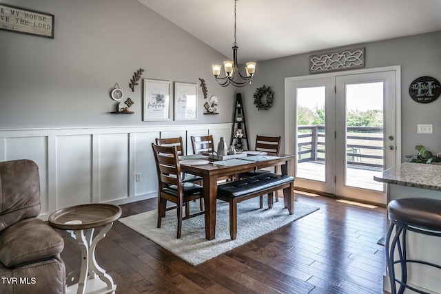 dining area with an inviting chandelier, vaulted ceiling, dark wood-style flooring, and a wainscoted wall