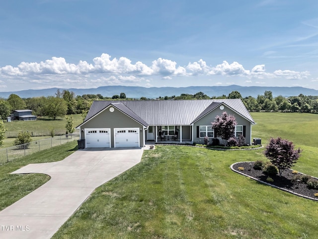 view of front of property with fence, a mountain view, driveway, a garage, and a front lawn