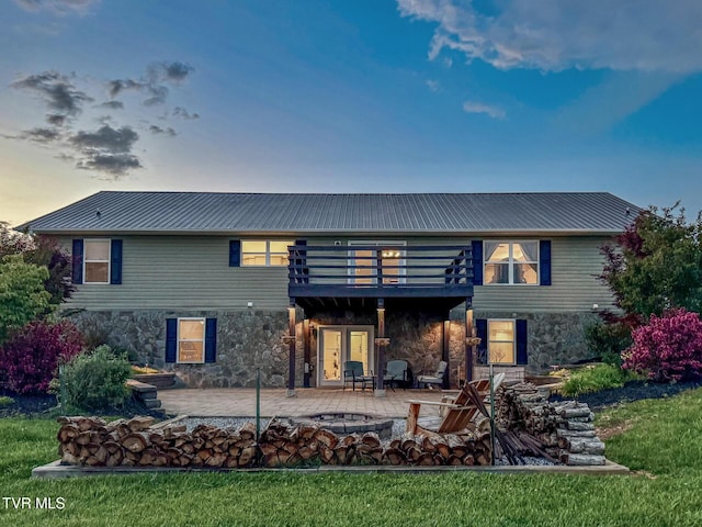 rear view of property featuring stone siding, a patio area, and metal roof