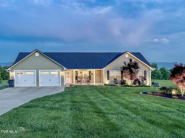 view of front facade featuring concrete driveway, metal roof, a front lawn, and a garage