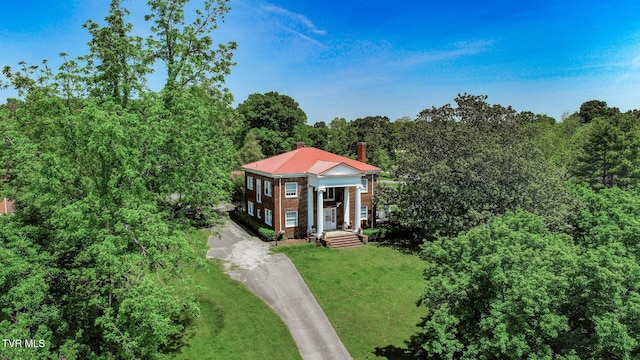 view of front of property with driveway, a chimney, and a front lawn