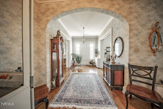 hallway with arched walkways, dark wood-style floors, and ornamental molding