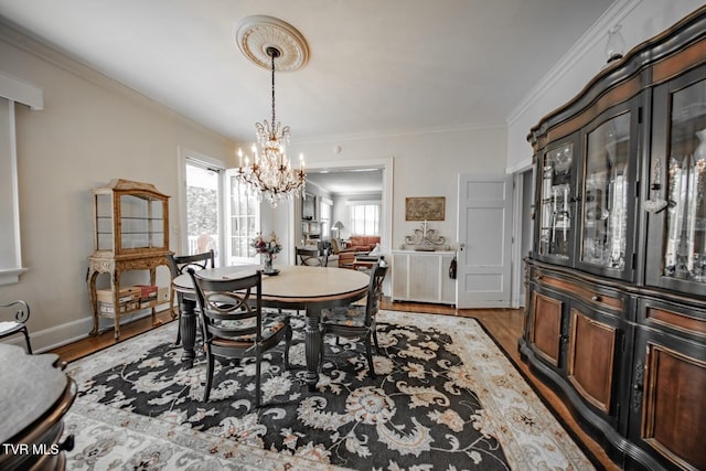 dining room featuring an inviting chandelier, baseboards, ornamental molding, and wood finished floors