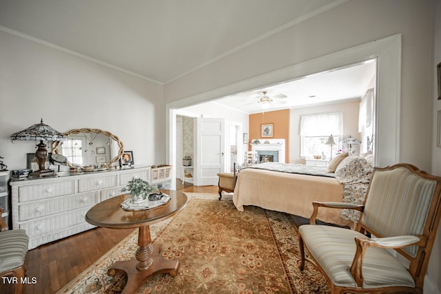 bedroom with crown molding, wood finished floors, and a fireplace