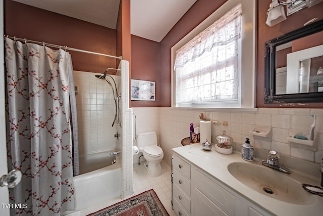bathroom with vanity, toilet, a wainscoted wall, tile walls, and shower / tub combo