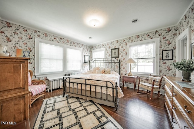 bedroom with wallpapered walls and dark wood finished floors
