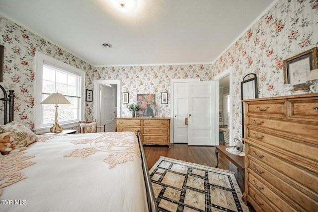 bedroom featuring crown molding, dark wood finished floors, visible vents, and wallpapered walls