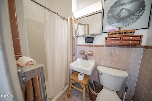 bathroom featuring toilet, a sink, tile walls, and curtained shower