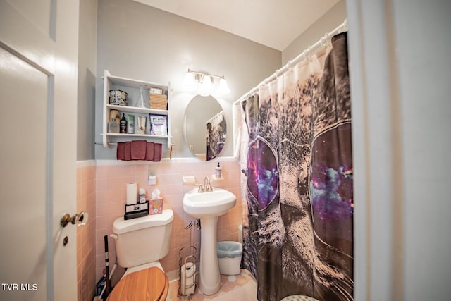 bathroom featuring a wainscoted wall, a shower with curtain, toilet, and tile walls