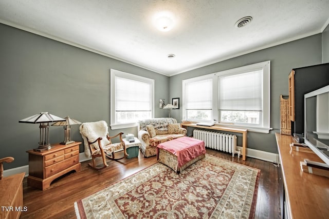 bedroom featuring baseboards, multiple windows, radiator heating unit, and wood finished floors