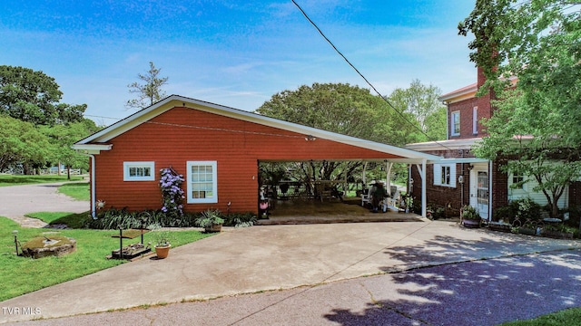 view of front of house with concrete driveway, an attached carport, and a front lawn