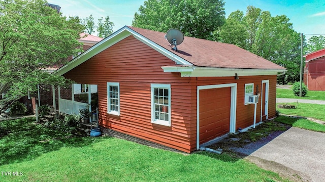view of side of property featuring roof with shingles, a lawn, a garage, cooling unit, and an outdoor structure