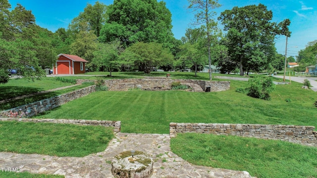 view of yard featuring a detached garage, an outdoor structure, and a storage unit