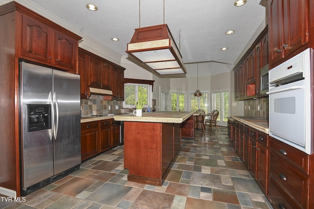 kitchen with decorative backsplash, a kitchen island, stainless steel refrigerator with ice dispenser, dark brown cabinets, and oven