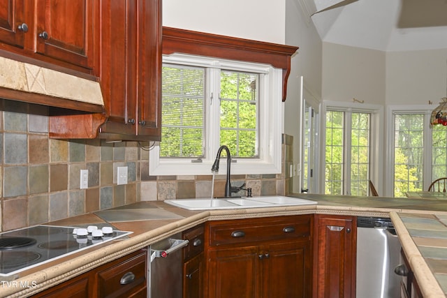 kitchen with black electric stovetop, a sink, light countertops, backsplash, and stainless steel dishwasher