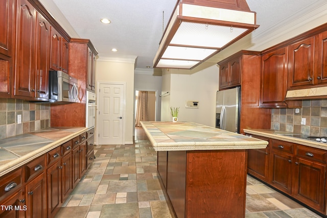 kitchen featuring a kitchen island, stone finish flooring, crown molding, appliances with stainless steel finishes, and light countertops
