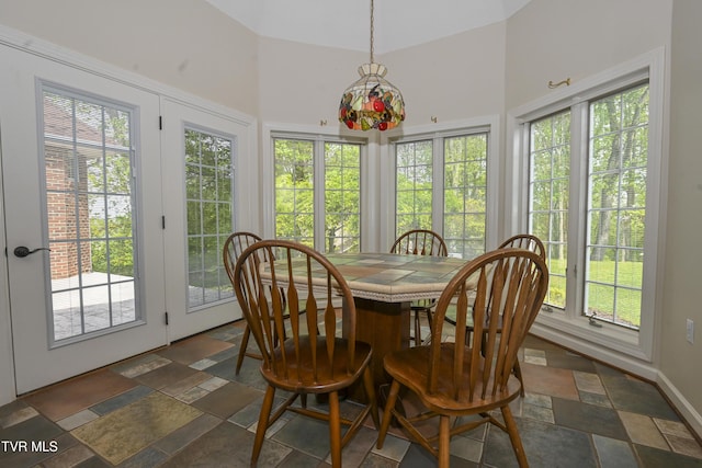 sunroom / solarium featuring plenty of natural light, french doors, stone tile flooring, and a high ceiling