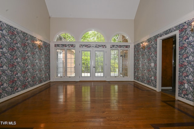 unfurnished room featuring baseboards, a high ceiling, wallpapered walls, and hardwood / wood-style floors