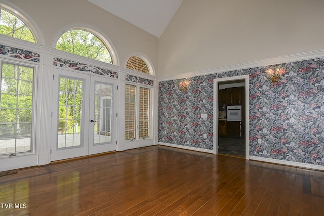 empty room featuring french doors, visible vents, high vaulted ceiling, wallpapered walls, and hardwood / wood-style floors