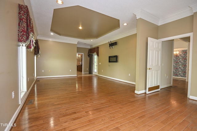 unfurnished room with baseboards, a raised ceiling, light wood-style flooring, and ornamental molding