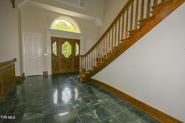 foyer entrance featuring baseboards, a high ceiling, and stairway