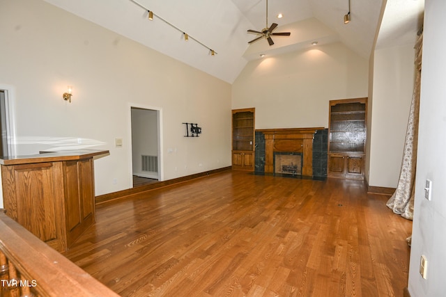 unfurnished living room with wood finished floors, a fireplace, baseboards, high vaulted ceiling, and a ceiling fan