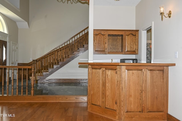 bar with wood finished floors, stairway, and a towering ceiling