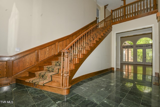 staircase featuring baseboards, visible vents, and a towering ceiling