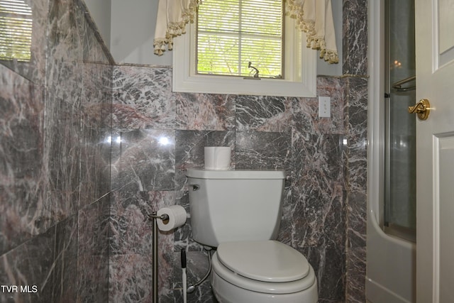 bathroom featuring tile walls and toilet