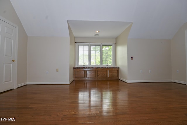 unfurnished living room with wood-type flooring, baseboards, and lofted ceiling