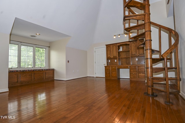 unfurnished living room with a high ceiling, built in study area, stairs, baseboards, and dark wood-type flooring