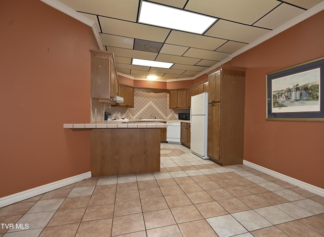 kitchen featuring light tile patterned flooring, white appliances, tile counters, a peninsula, and tasteful backsplash