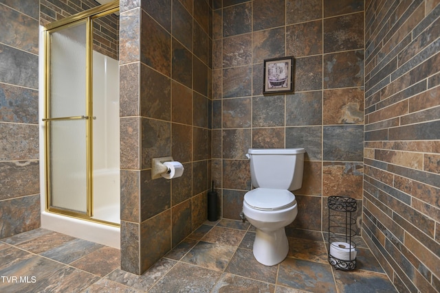 full bathroom featuring toilet, tile walls, a shower stall, and stone finish floor