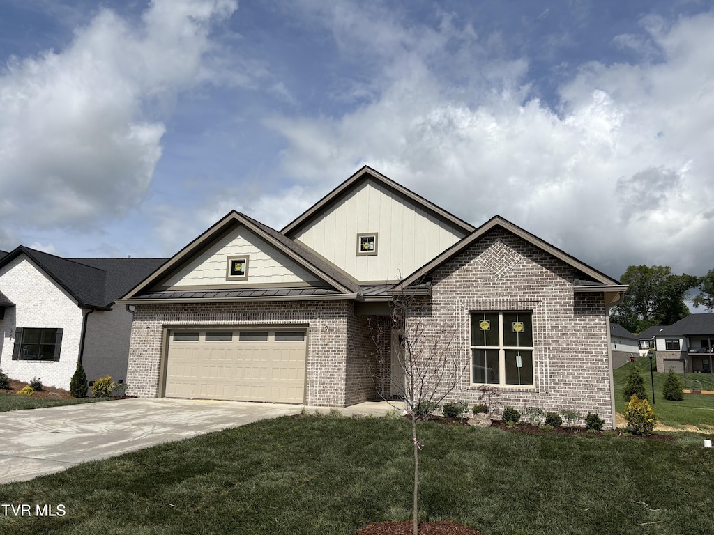 view of front facade with a front lawn, a standing seam roof, brick siding, board and batten siding, and driveway