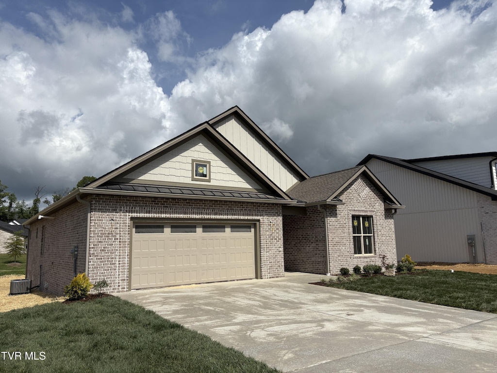single story home with brick siding, a front lawn, driveway, and a standing seam roof