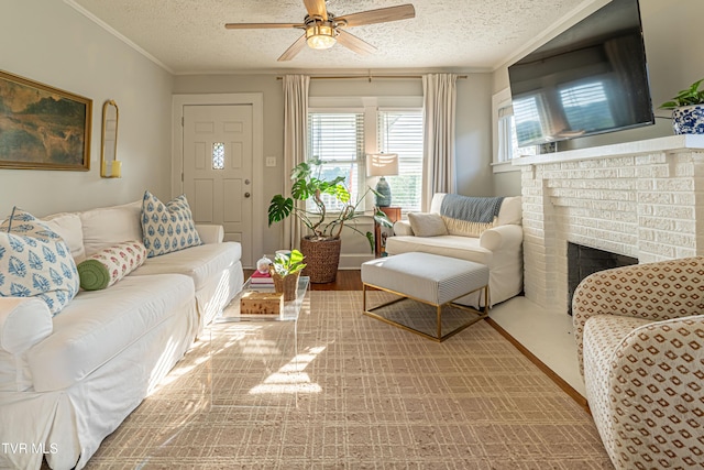 living room featuring ceiling fan, ornamental molding, a brick fireplace, and a textured ceiling