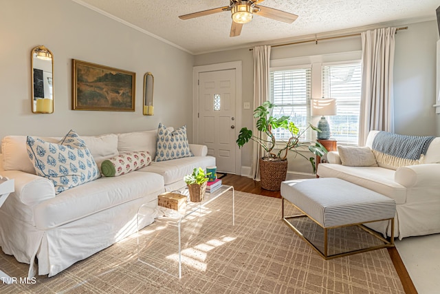 living area featuring a ceiling fan, a textured ceiling, wood finished floors, and ornamental molding
