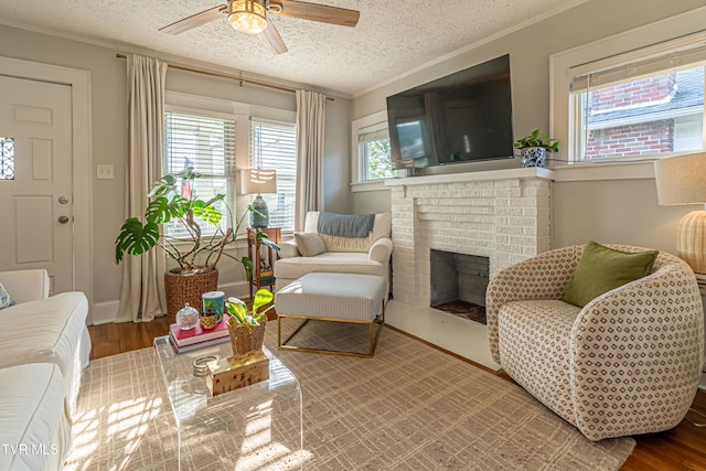 living room with a ceiling fan, a textured ceiling, wood finished floors, and a fireplace