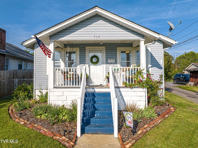 view of front of property featuring a porch, a front lawn, and fence