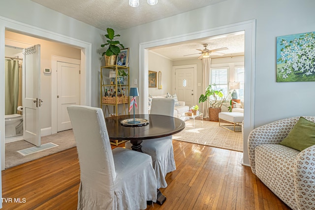 dining room featuring a ceiling fan, hardwood / wood-style flooring, a textured ceiling, and visible vents