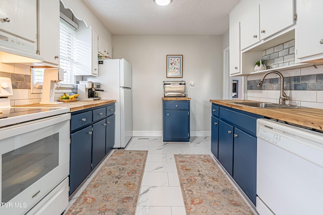kitchen featuring a sink, white appliances, butcher block countertops, marble finish floor, and blue cabinets