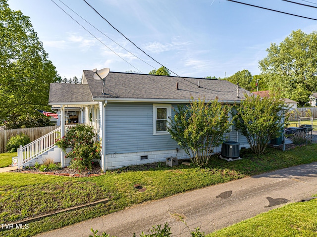 view of side of property with central air condition unit, a shingled roof, fence, and crawl space