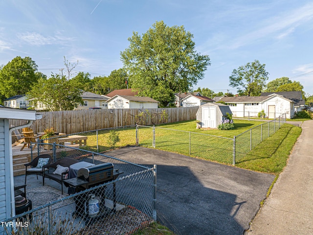view of yard featuring a storage shed, an outdoor structure, a residential view, and a fenced backyard