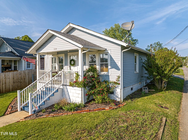 bungalow-style home with a front lawn, fence, covered porch, and crawl space